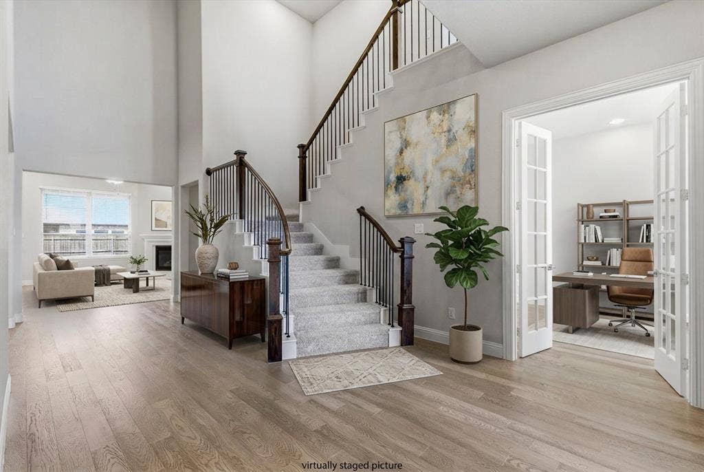 Two-story foyer with wood-finish flooring and a curved staircase featuring dark wood newel posts and metal spindles