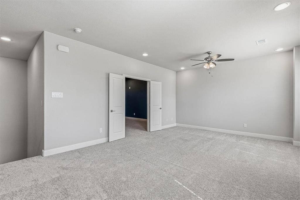 Spacious carpeted room featuring recessed lighting, a ceiling fan, and double panel doors