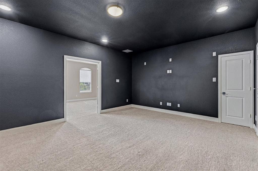 Recessed lighting, flush mount lighting, textured walls, light-toned carpeting, and a white interior door