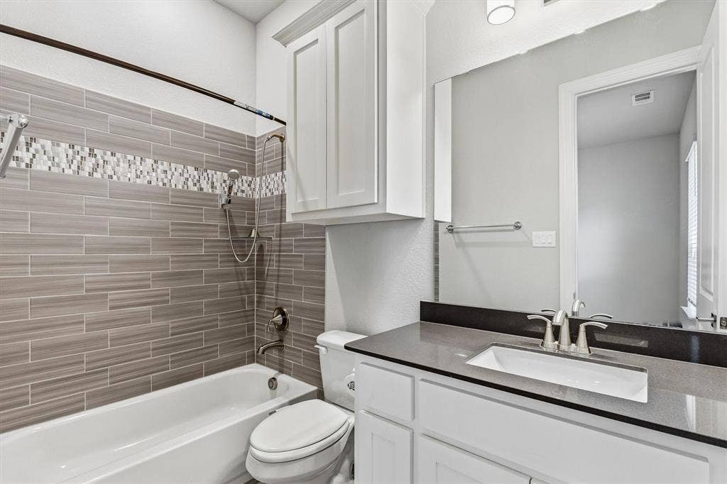 White vanity with an undermount sink, brushed nickel faucet, and a dark stone countertop