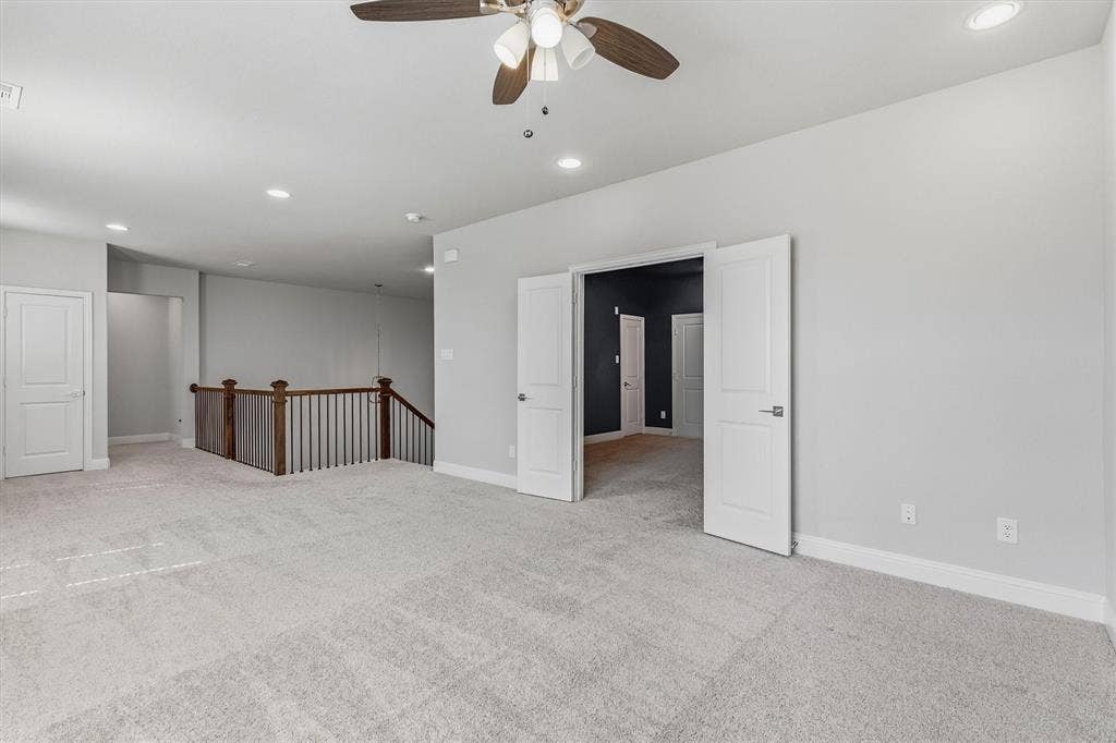 Spacious room with light gray carpeting, recessed lighting, and a ceiling fan