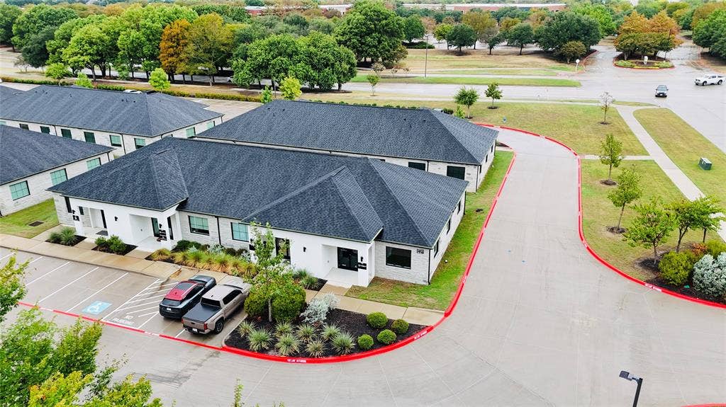 3721 S Stonebridge Drive, #704, McKinney, TX 75070 White stone exterior, dark shingled roofs, ample surface parking, paved driveways, and landscaped grounds