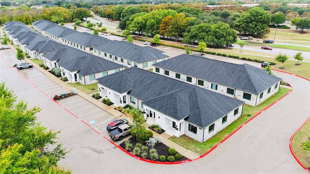 3721 S Stonebridge Drive, #704, McKinney, TX 75070 Multiple single-story structures with dark shingle roofs, white exteriors, and green landscaping