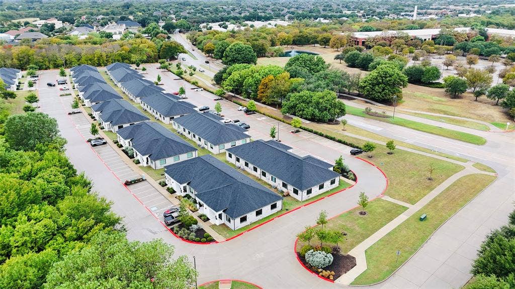 3721 S Stonebridge Drive, #704, McKinney, TX 75070 Rows of single-story buildings with dark shingle roofs, white exteriors, and individual parking spaces