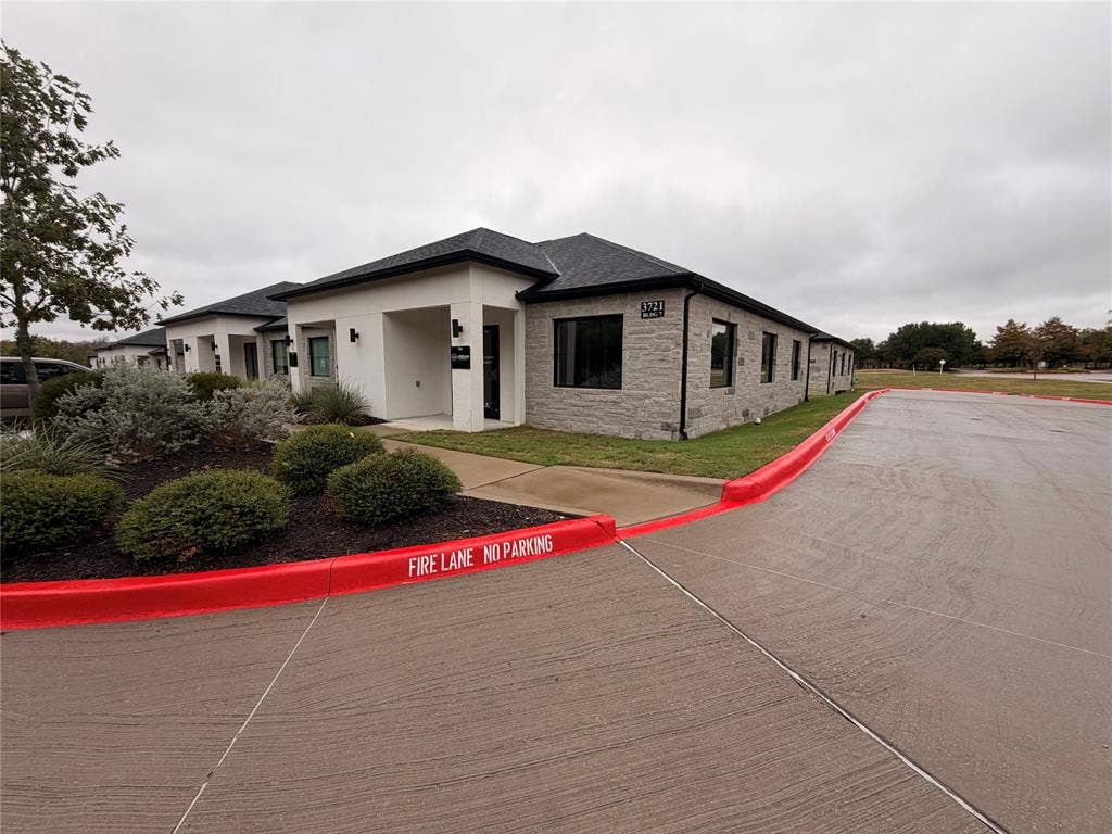 3721 S Stonebridge Drive, #704, McKinney, TX 75070 Modern stucco and stone-clad exterior with dark-framed windows, a dark shingle roof, and established landscaping