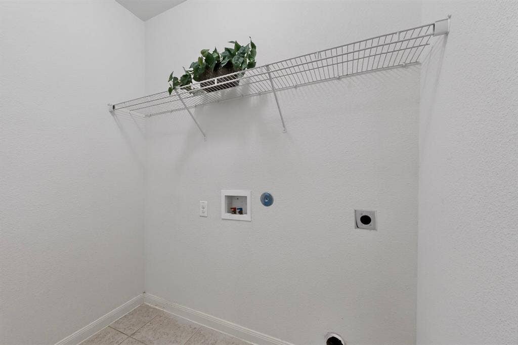 215 Magnolia Drive, Princeton, TX 75407 White wire shelving unit over utility hookups, complemented by light-toned tile flooring