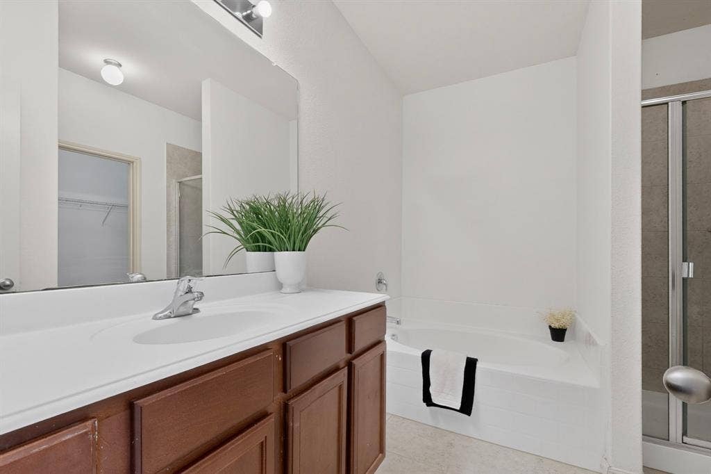 215 Magnolia Drive, Princeton, TX 75407 Integrated vanity with a single basin, dark wood-finish cabinetry, and a full-width mirror