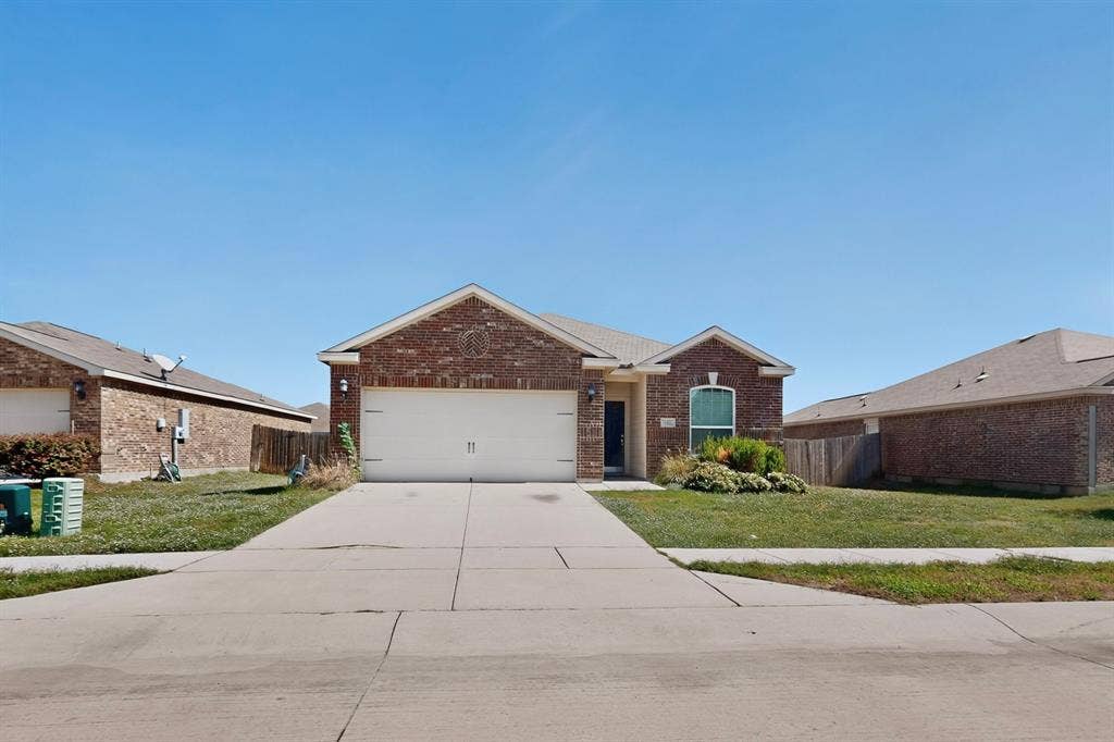215 Magnolia Drive, Princeton, TX 75407 Brick exterior with an attached two-car garage, concrete driveway, and front lawn