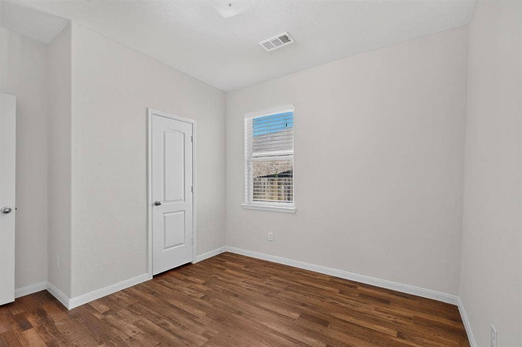 215 Magnolia Drive, Princeton, TX 75407 Wood-finish flooring, white paneled door, white trim, single window with blinds, and light-toned walls
