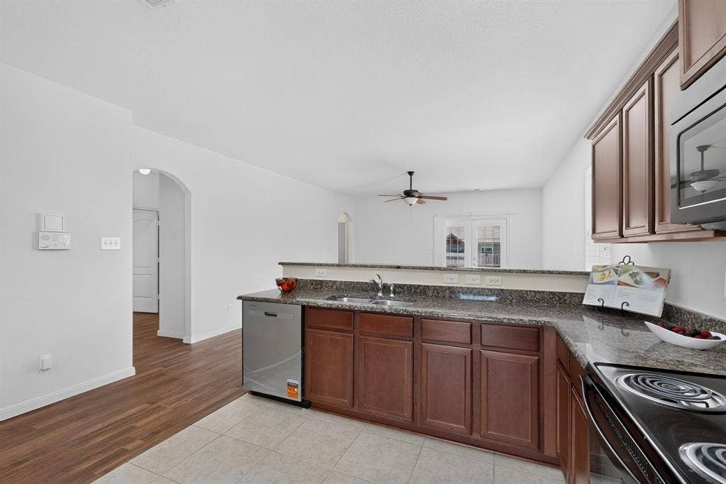 215 Magnolia Drive, Princeton, TX 75407 Kitchen featuring a stainless steel dishwasher, brown cabinetry, and speckled countertops