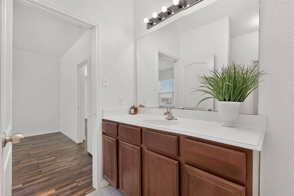 215 Magnolia Drive, Princeton, TX 75407 Bathroom vanity with a white countertop, under-mount sink, and wood-finish cabinetry