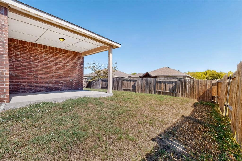 215 Magnolia Drive, Princeton, TX 75407 Covered patio with a concrete slab, red brick exterior, and a wood-tone support post