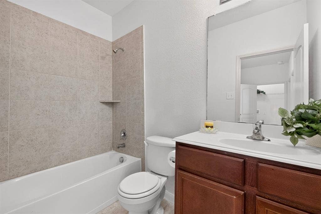 215 Magnolia Drive, Princeton, TX 75407 White bathtub with light-colored tile surround and built-in shelf
