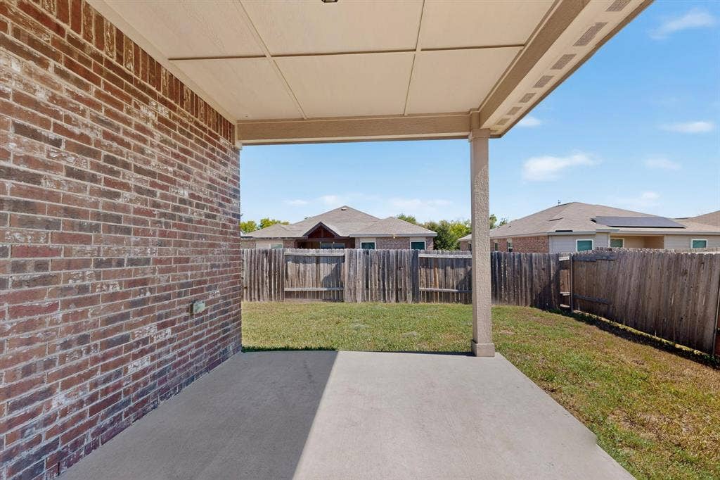 215 Magnolia Drive, Princeton, TX 75407 Covered patio with a concrete slab, brick exterior, and a fenced backyard