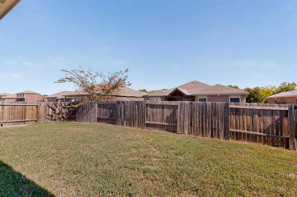 215 Magnolia Drive, Princeton, TX 75407 Enclosed backyard featuring wood privacy fencing and a grass lawn