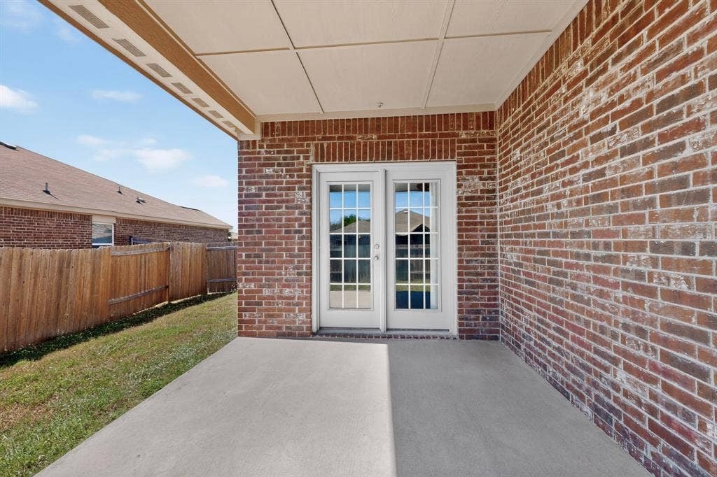 215 Magnolia Drive, Princeton, TX 75407 Brick exterior with covered patio, concrete surface, and French doors