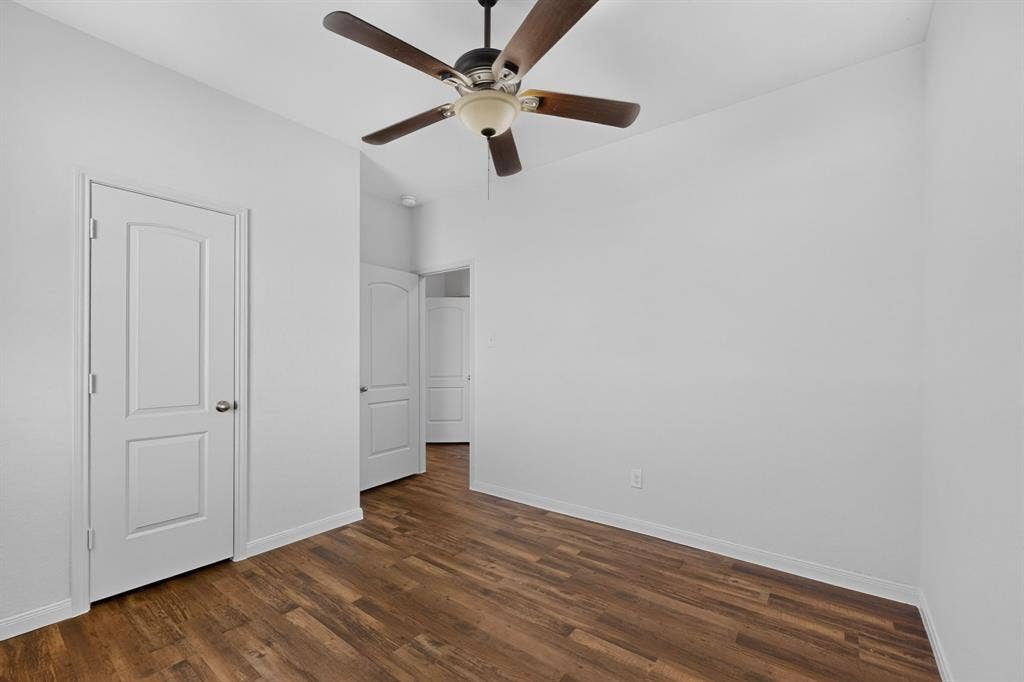 215 Magnolia Drive, Princeton, TX 75407 Wood-finish flooring with white baseboards, a ceiling fan with light fixture, and white interior doors with satin nickel hardware