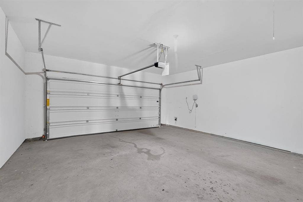 215 Magnolia Drive, Princeton, TX 75407 Spacious garage with a concrete floor, white painted walls, and an overhead garage door system