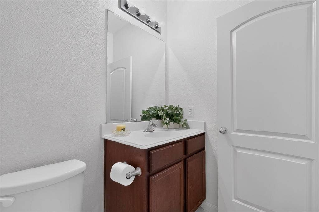 215 Magnolia Drive, Princeton, TX 75407 White paneled door with an arched top frame, chrome door hardware, wood-finish vanity with a white countertop and integrated sink, and a chrome faucet