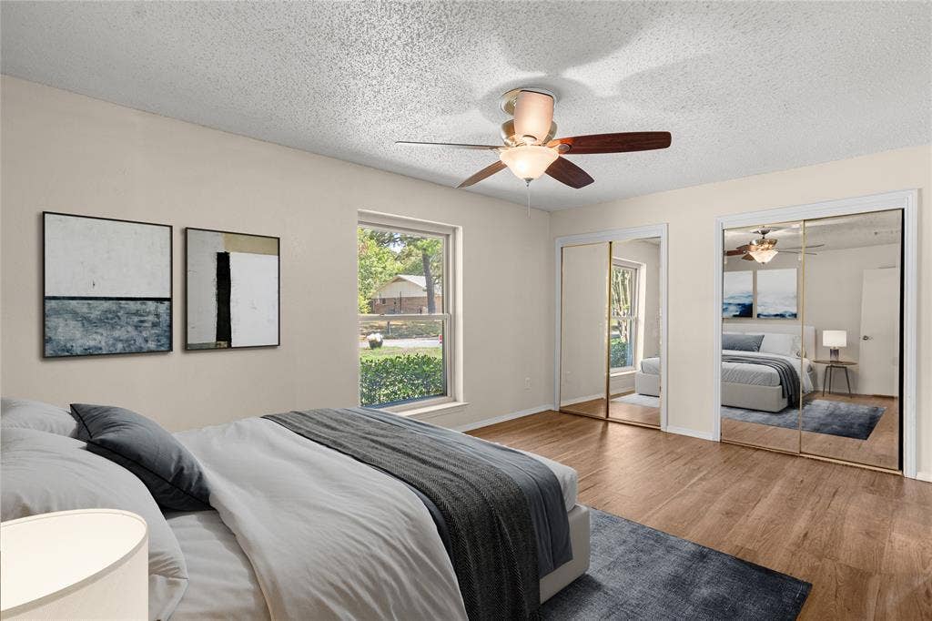 2004 Ford Street, Arlington, TX 76013 Virtually Staged Bedroom with Wood-finish flooring, ceiling fan with integrated lighting, window with exterior landscape, and mirrored closet doors