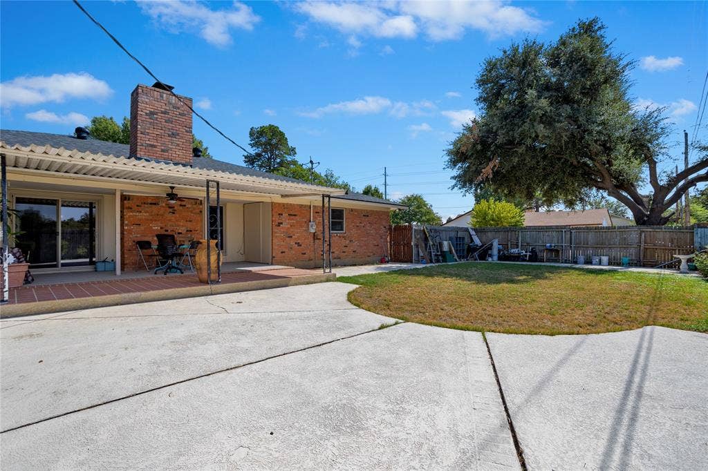 2004 Ford Street, Arlington, TX 76013 Brick exterior with a covered patio, featuring a brick chimney, sliding glass door, and an expansive concrete patio