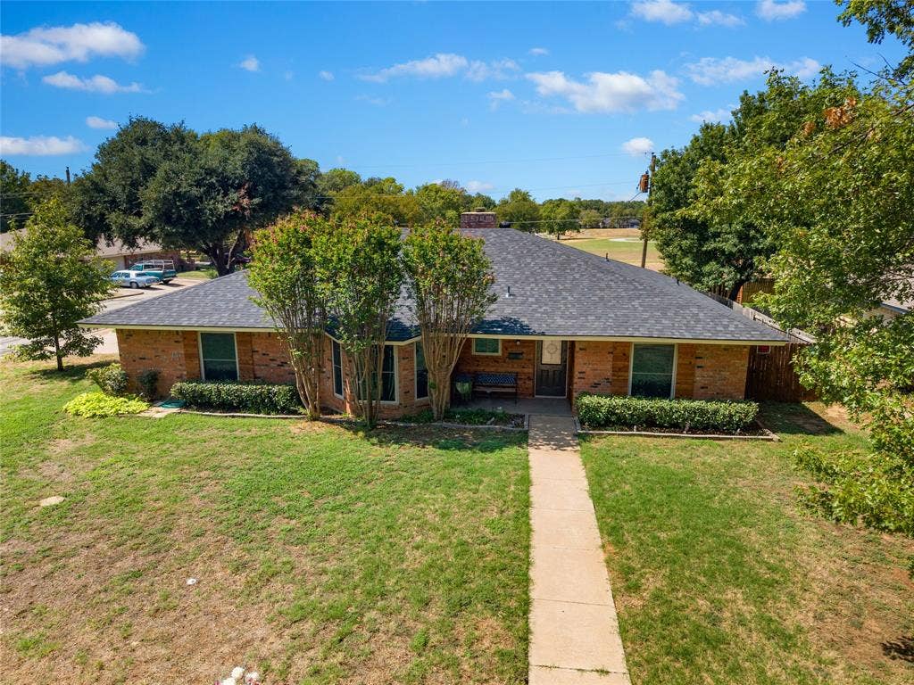 2004 Ford Street, Arlington, TX 76013 Brick exterior with a dark shingle roof, mature landscaping, and a concrete walk leading to the front entry