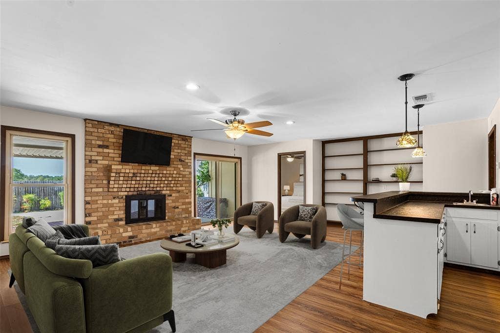 2004 Ford Street, Arlington, TX 76013 Virtually Staged Living area featuring a brick fireplace, wood-finish flooring, built-in shelving, and a wet bar with pendant lighting