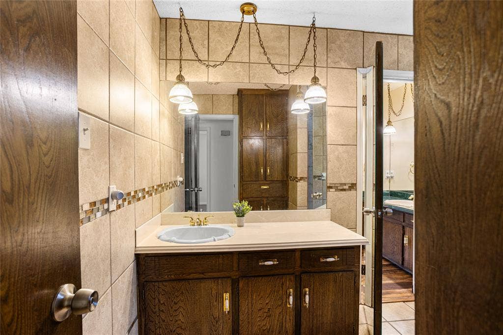 2004 Ford Street, Arlington, TX 76013 Wood-finish vanity with a recessed sink and single-handle faucet, complemented by a large wall-mounted mirror