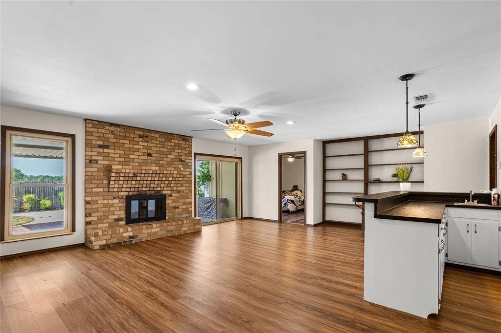 2004 Ford Street, Arlington, TX 76013 Wood-finish flooring throughout, brick fireplace, built-in shelving, white cabinetry, and sliding glass door