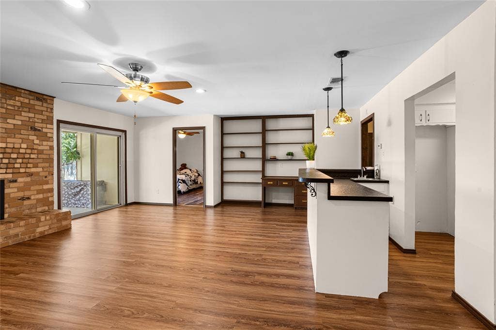 2004 Ford Street, Arlington, TX 76013 Wood-finish flooring throughout, with an exposed brick fireplace, built-in shelving, and a breakfast bar featuring pendant lighting