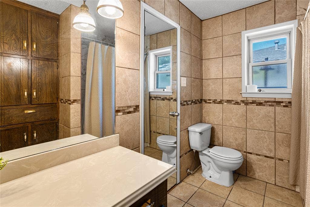 2004 Ford Street, Arlington, TX 76013 Full-height wood cabinetry, tiled walls with decorative mosaic accents, and a vanity with an integrated sink