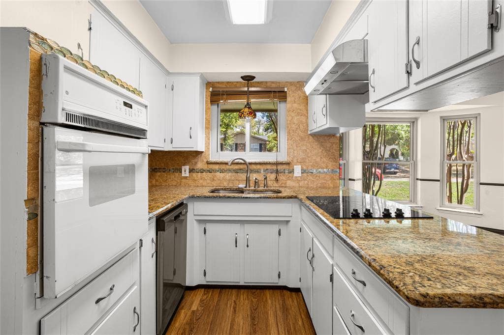 2004 Ford Street, Arlington, TX 76013 White cabinetry, stone-finish countertops, wood-finish flooring, built-in oven, and a cooktop