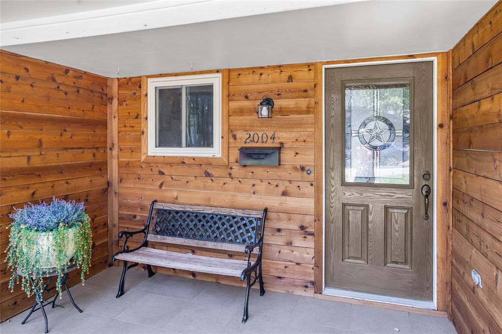 2004 Ford Street, Arlington, TX 76013 Wood-paneled entryway featuring a gray panel door with decorative glass, a porch light fixture, and a front window