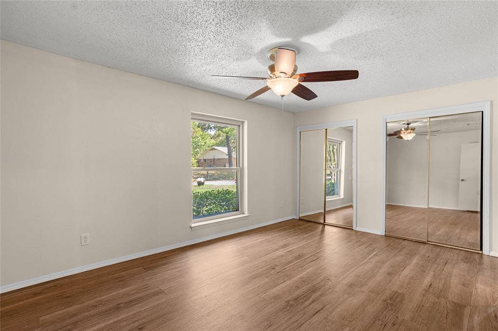 2004 Ford Street, Arlington, TX 76013 Wood-finish flooring, a window offering exterior views, a ceiling fan with integrated lighting, and mirrored sliding closet doors