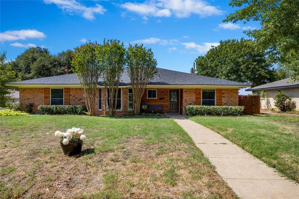 2004 Ford Street, Arlington, TX 76013 Brick exterior with a dark shingle roof, established landscaping, and a concrete pathway