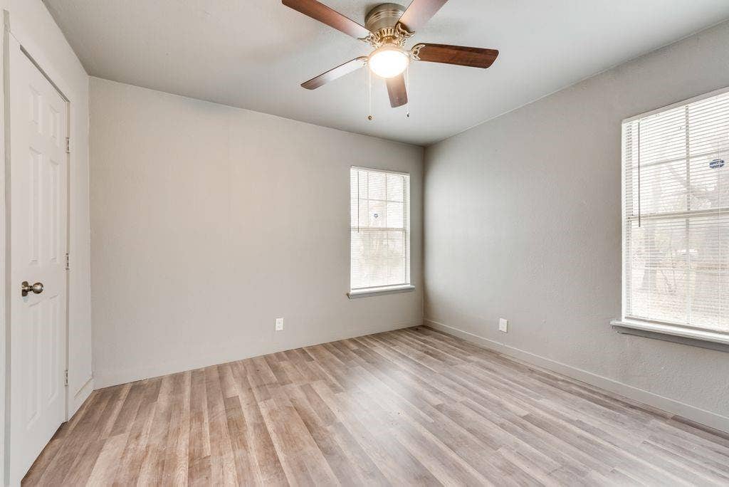 4414 Cinda Ree Lane, Dallas, TX 75216 Wood-finish flooring, two windows with blinds, and a ceiling fan with integrated lighting