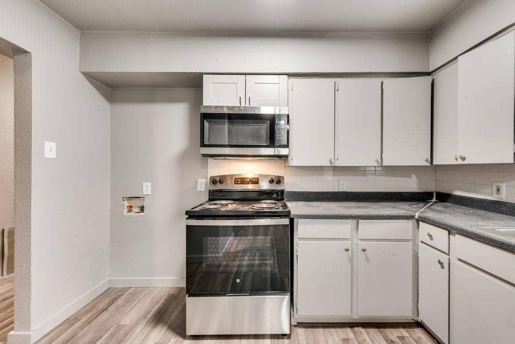 4414 Cinda Ree Lane, Dallas, TX 75216 Kitchen featuring wood-finish flooring, white cabinetry, a stainless steel oven/range, a built-in microwave, and dark countertops
