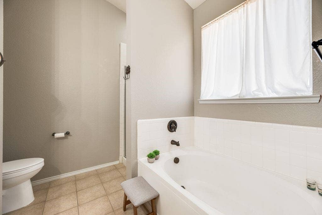 1323 Canyon Creek Road, Wylie, TX 75098 Integrated soaking tub with dark bronze fixtures, white tile surround, and a clear glass shower enclosure