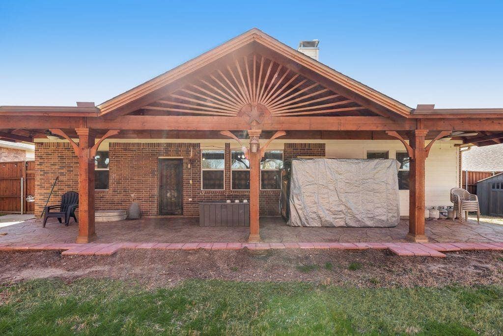 1323 Canyon Creek Road, Wylie, TX 75098 Spacious covered patio with wood-finish pergola structure, brick exterior, multiple windows, and a privacy fence