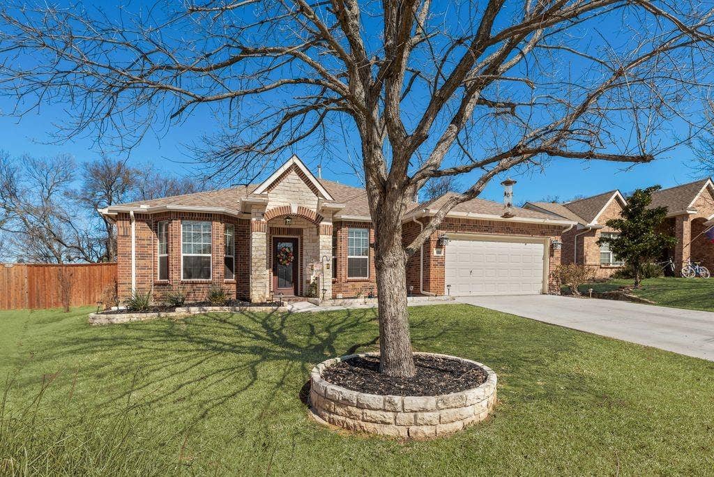 1323 Canyon Creek Road, Wylie, TX 75098 Brick and stone facade, arched entryway, bay window, two-car garage, and a manicured lawn