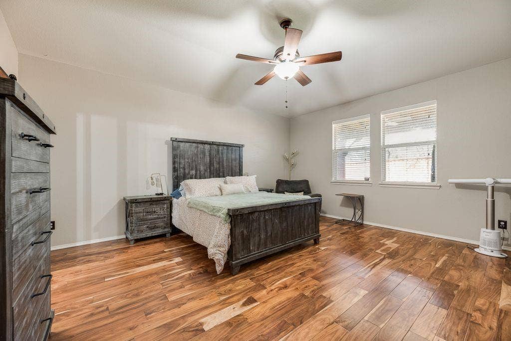 1323 Canyon Creek Road, Wylie, TX 75098 Wood-finish flooring, two large windows, vaulted ceiling, and a ceiling fan with integrated lighting