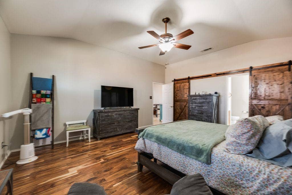 1323 Canyon Creek Road, Wylie, TX 75098 Vaulted ceiling, ceiling fan, wood-finish flooring, wood barn doors, and a white door