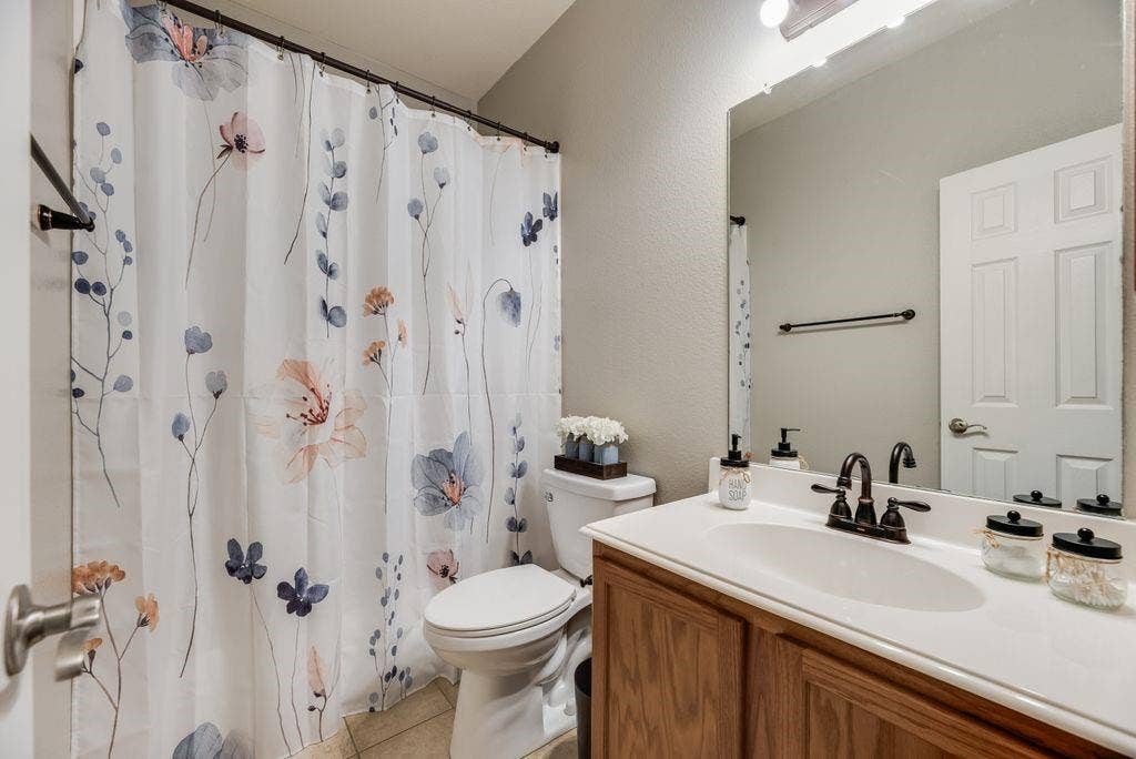 1323 Canyon Creek Road, Wylie, TX 75098 White vanity with a single basin sink, bronze-finish faucet, and wood-finish cabinetry