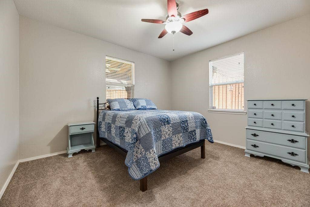 1323 Canyon Creek Road, Wylie, TX 75098 Carpeted room with a ceiling fan, two windows with blinds, and light-toned walls