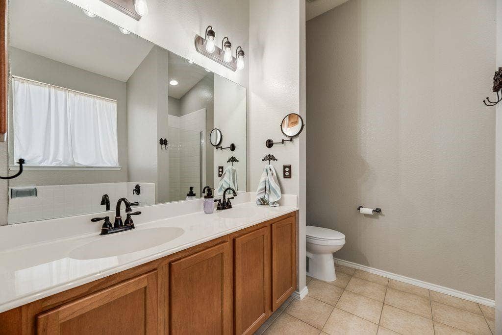 1323 Canyon Creek Road, Wylie, TX 75098 Dual vanity with integrated sinks, wood cabinetry, and oil-rubbed bronze fixtures