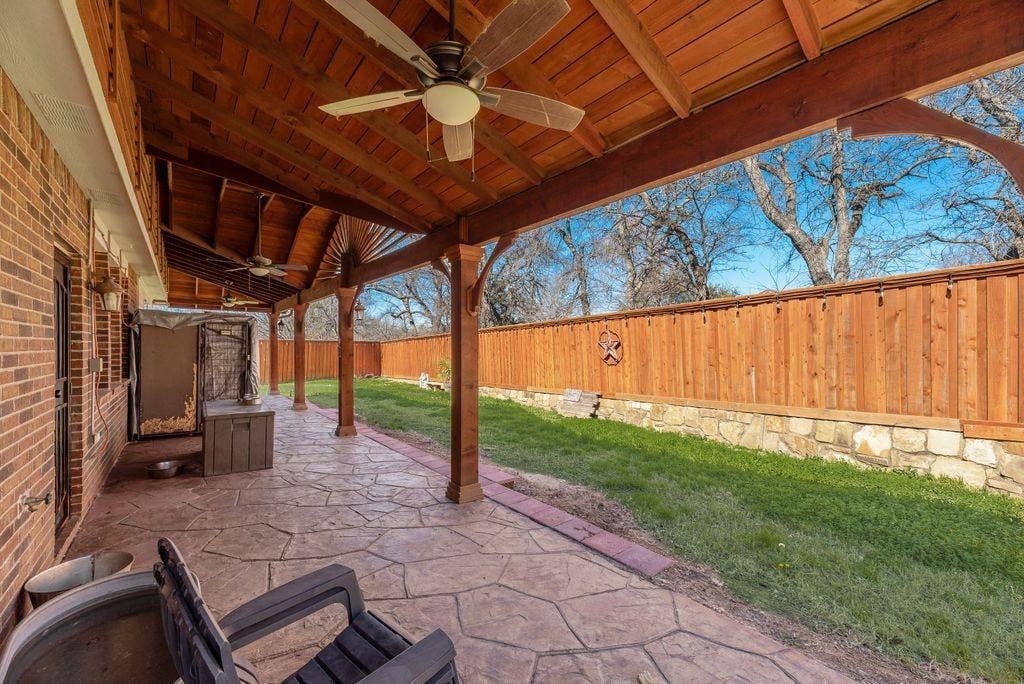 1323 Canyon Creek Road, Wylie, TX 75098 Expansive covered patio featuring a stamped concrete surface, ceiling fans, and exposed wood beam construction