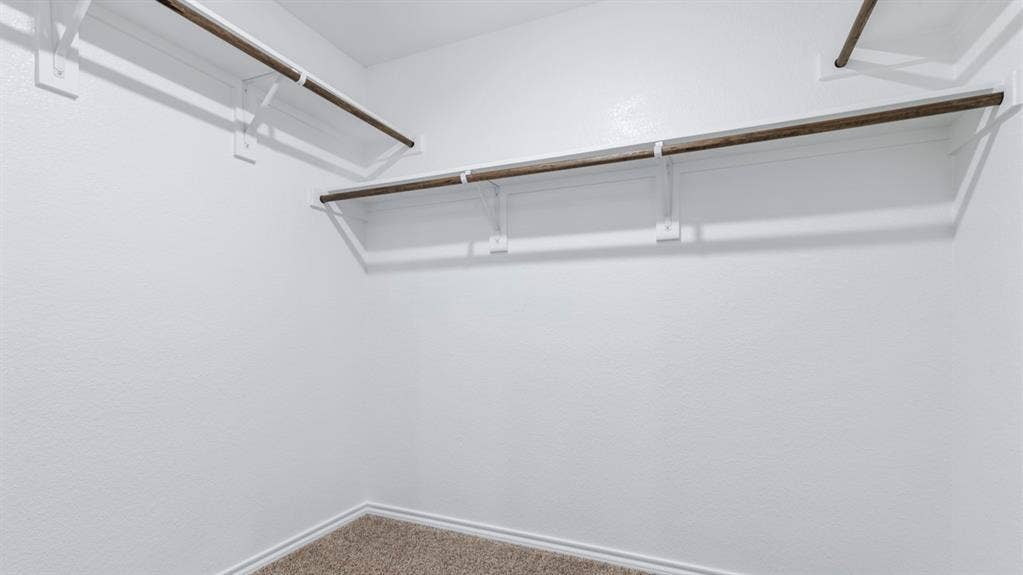 5012 Shumard Drive, Lindale, TX 75771 Spacious closet with multiple hanging rods, white shelving, and carpet flooring