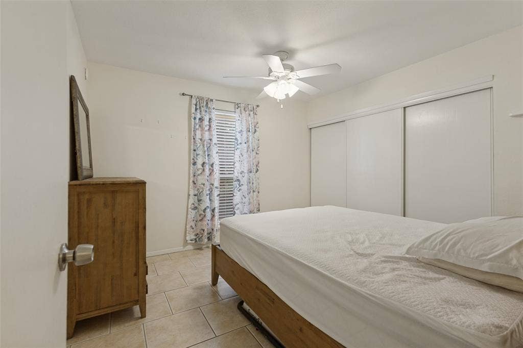 5981 Arapaho Road, #103, Dallas, TX 75248 Tile flooring, window with blinds, ceiling fan with light fixture, and sliding closet doors