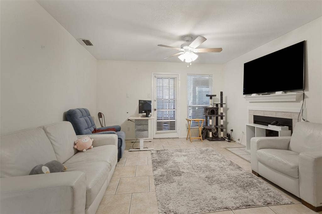 5981 Arapaho Road, #103, Dallas, TX 75248 Tile flooring, recessed fireplace with mantle, ceiling fan, and two windows with blinds