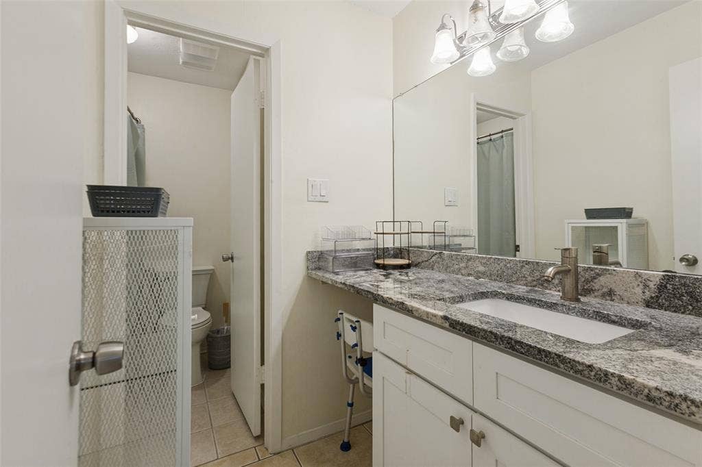 5981 Arapaho Road, #103, Dallas, TX 75248 Vanity featuring a stone countertop, an undermount sink, and a brushed nickel faucet
